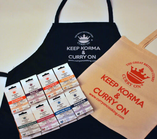 Black apron with curry on cooking logo with wording Keep Korma and Curry On with a cream shopper and 8 Curry On Cooking curry kits