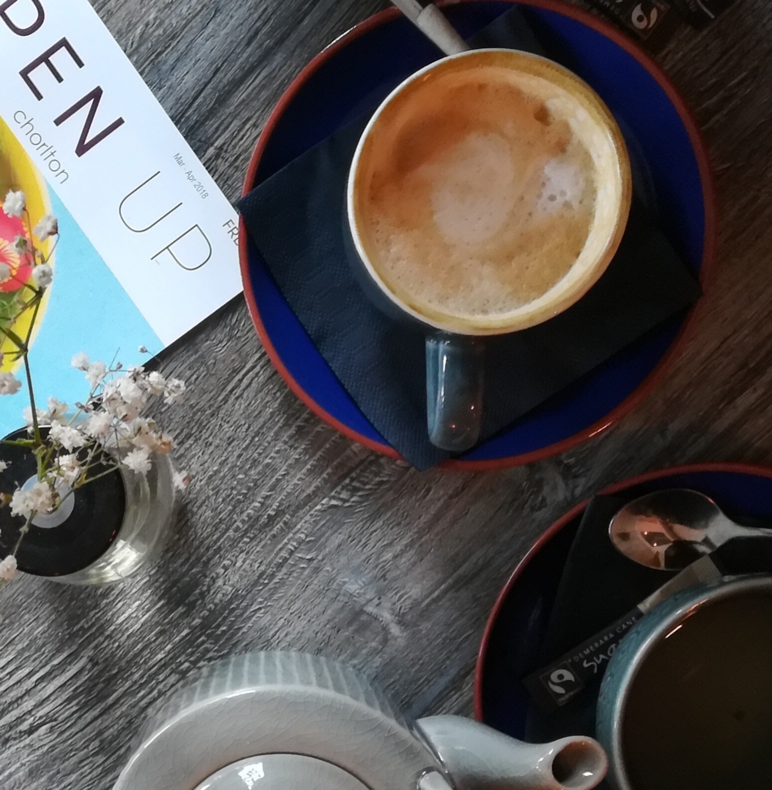 Masala Chai cup and saucer with tea on a table with teapot and magazine