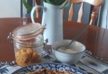 Indian stuffed flatbread on plate on table with pickle jar plus a jug of tulips